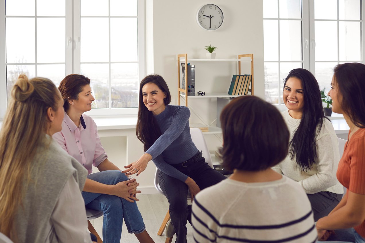 Smiling Coach, Therapist or Team Manager Supporting Women in Group Therapy or Corporate Meeting