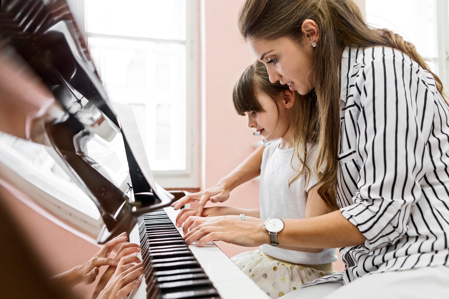 Young woman piano teacher educating child